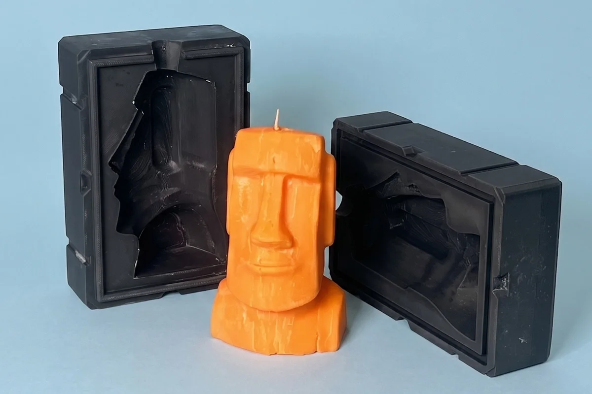 A Moai candle cast from a 3DGEN mold, standing between its two printed mold halves